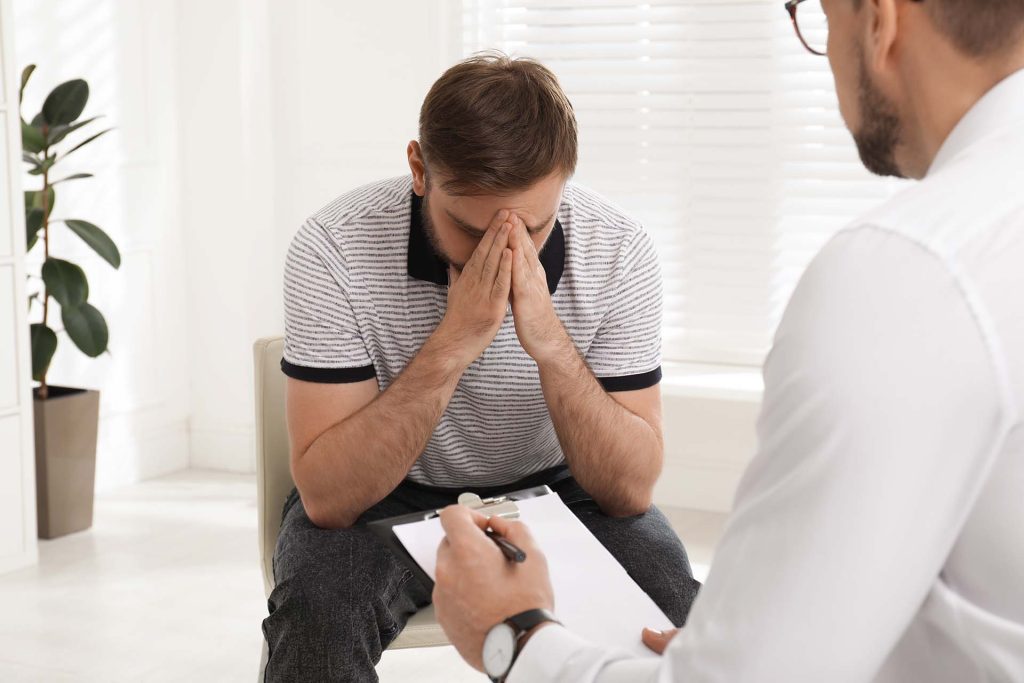 Personalized Addiction Treatment - Psychotherapist working with drug addicted young man indoors
